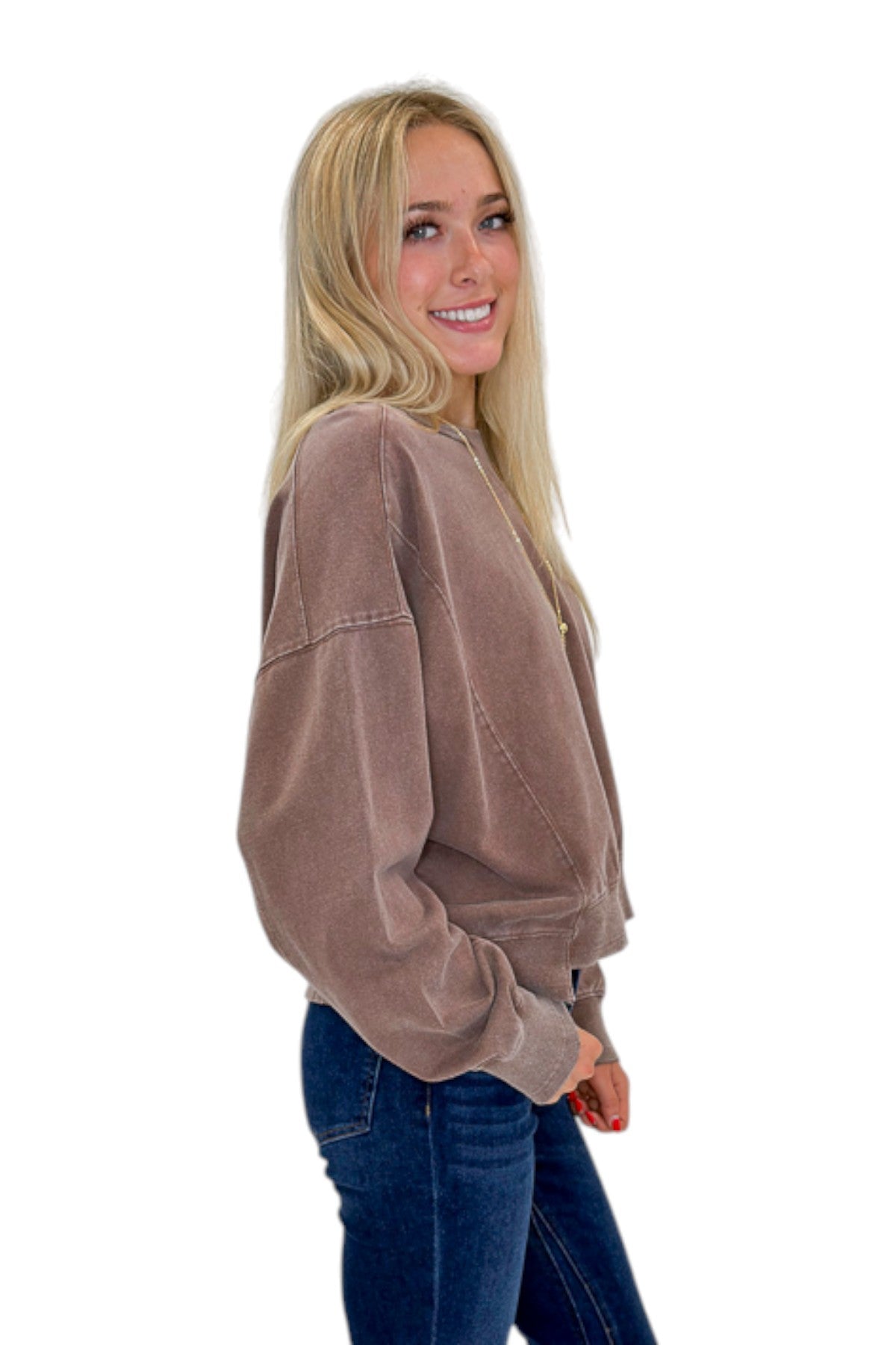 Side view of woman wearing Swagger Boutique’s Brown Ribbed Detail Sweatshirt with jeans against white studio background.