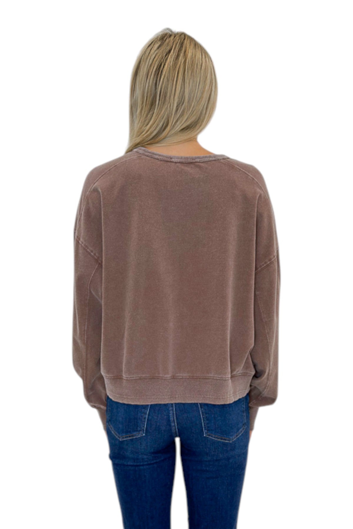 Back view of woman wearing Swagger Boutique’s Brown Ribbed Detail Sweatshirt with jeans against white studio background.