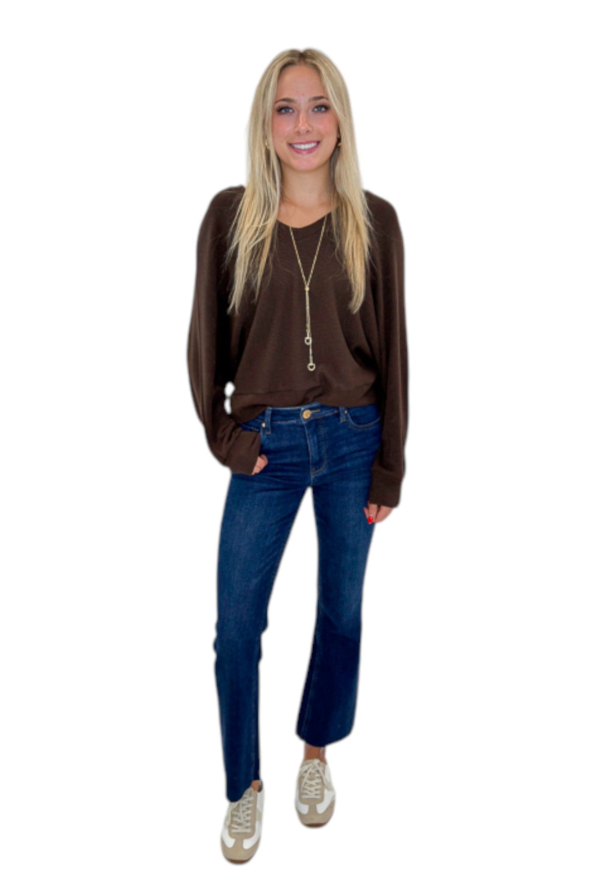 Front view of woman wearing Swagger Boutique’s Brown Ribbed V-neck Banded Top with jeans against white studio background.