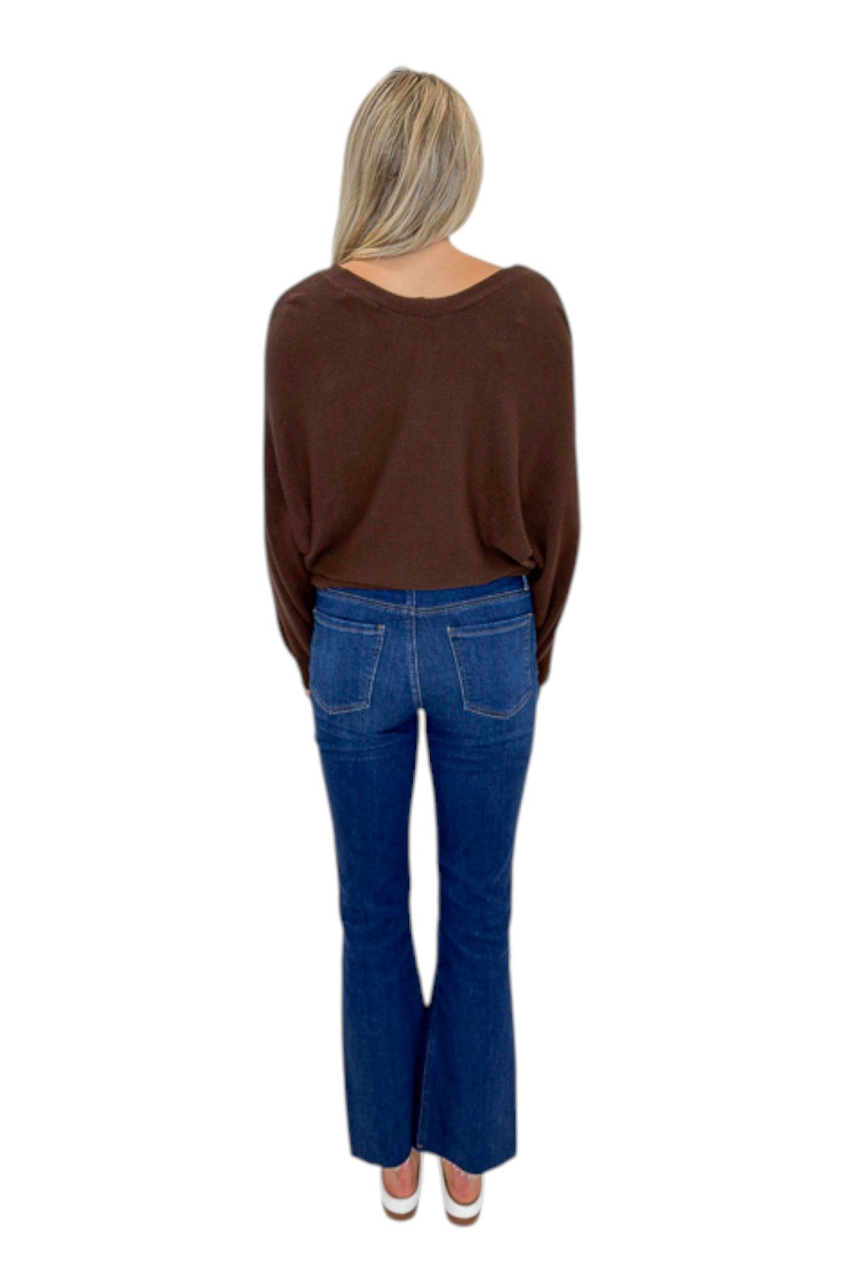 Back view of woman wearing Swagger Boutique’s Brown Ribbed V-neck Banded Top with jeans against white studio background.