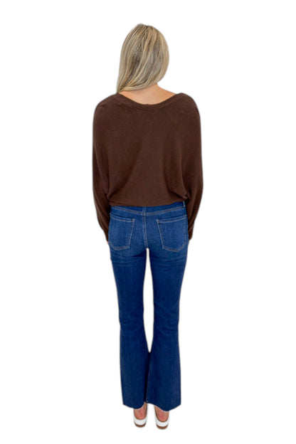 Back view of woman wearing Swagger Boutique’s Brown Ribbed V-neck Banded Top with jeans against white studio background.