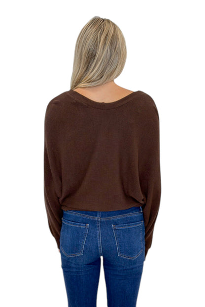 Back view of woman wearing Swagger Boutique’s Brown Ribbed V-neck Banded Top with jeans against white studio background.