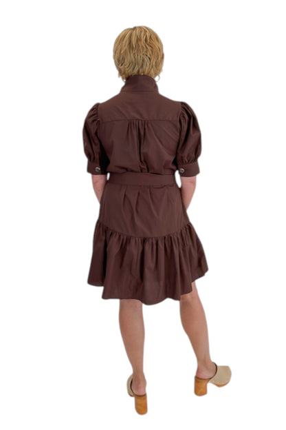 Back view of woman wearing Swagger Boutique’s Brown Ruffle Mini Dress by Entro against white studio background.