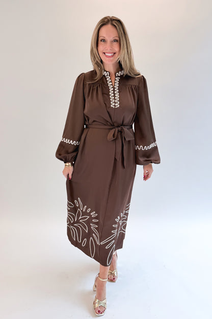 Front view of woman wearing Swagger Boutique’s Brown Satin Embroidered Midi Dress with heels against white studio background.