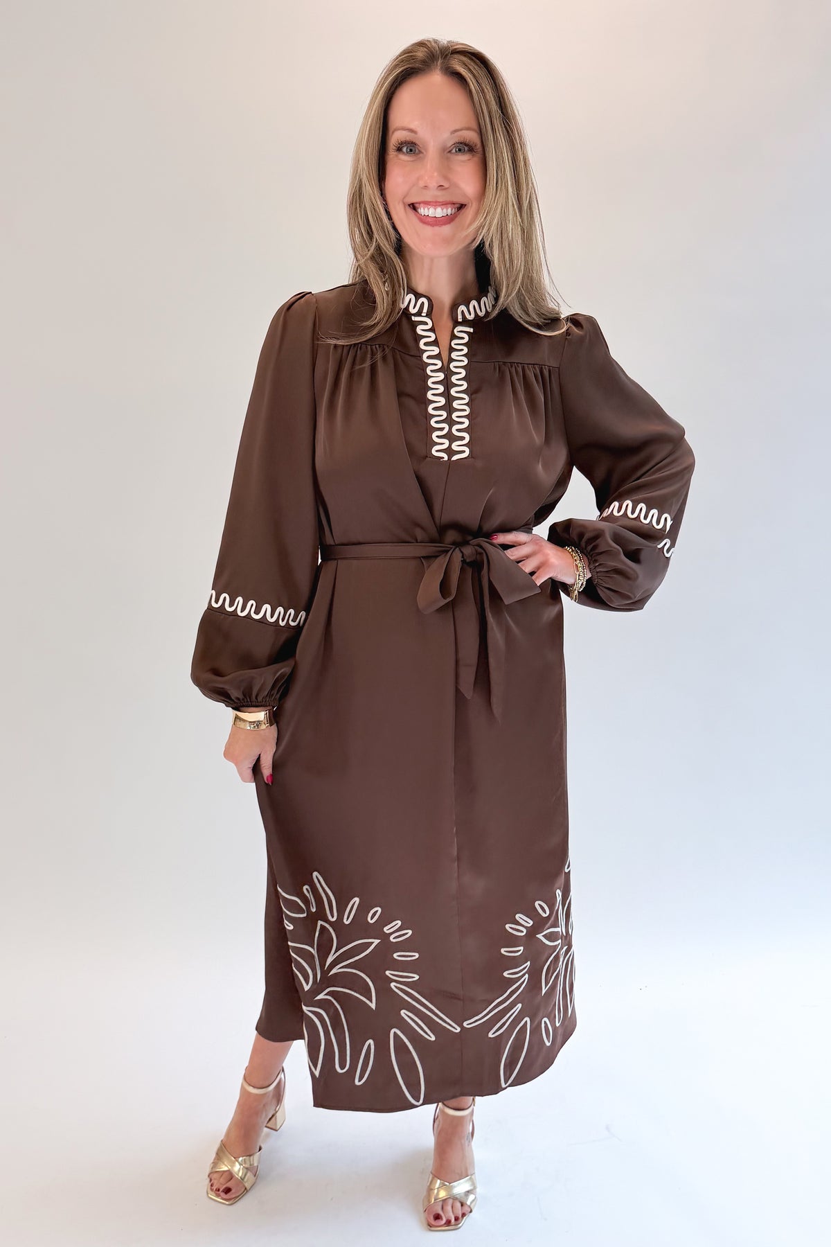 Front view of woman wearing Swagger Boutique’s Brown Satin Embroidered Midi Dress with heels against white studio background.
