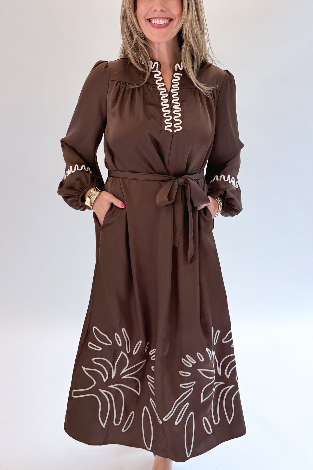 Front detail view of woman wearing Swagger Boutique’s Brown Satin Embroidered Midi Dress with heels against white studio background.