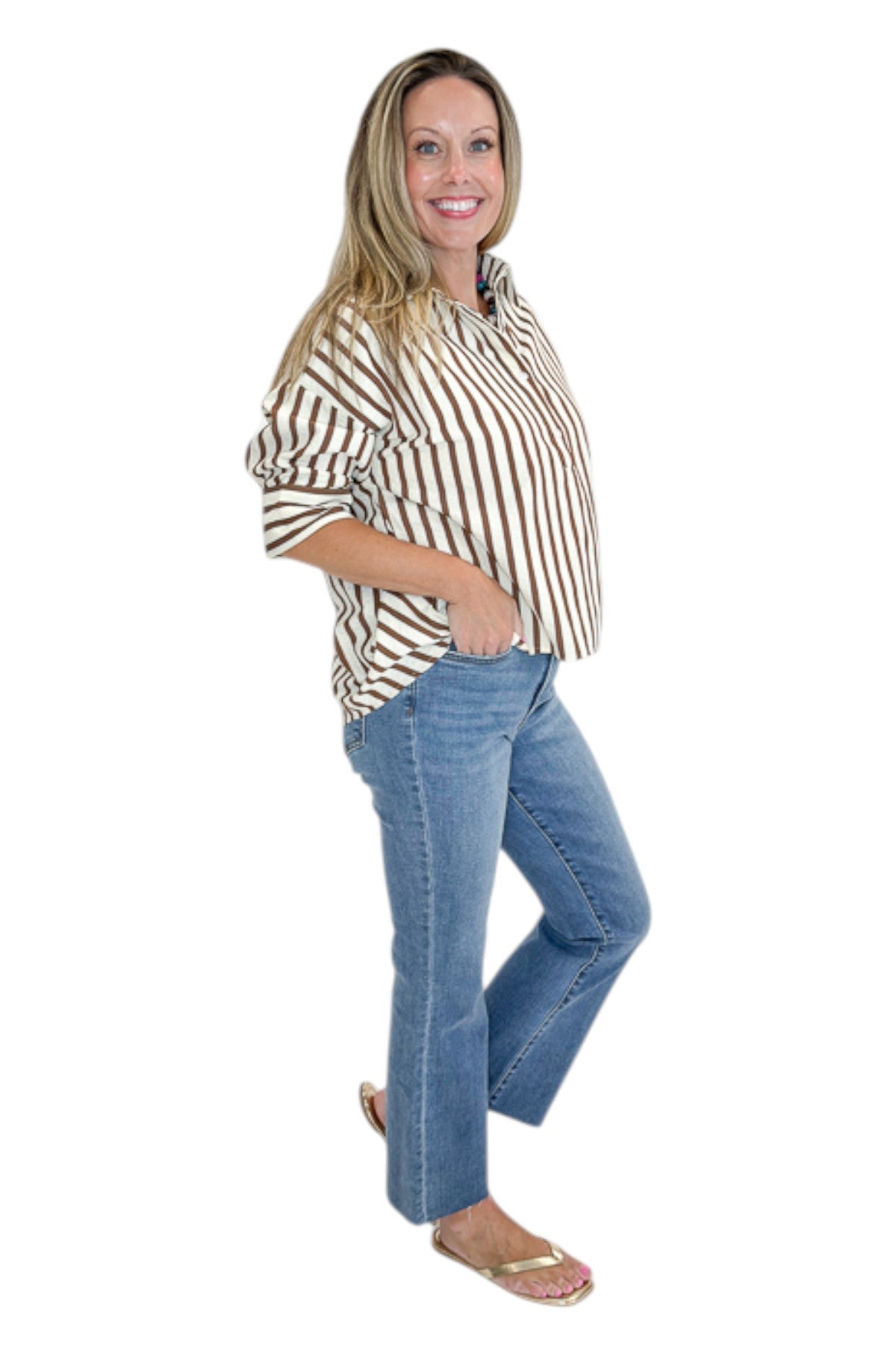 Side view of woman wearing Swagger Boutique’s Brown Striped 3/4 Sleeve Top with jeans against white studio background.