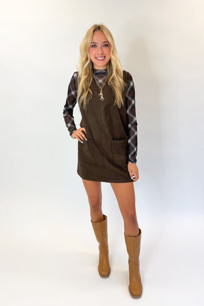 Front view of woman wearing Swagger Boutique’s Brown Suede V-Neck Mini Dress with Navy Plaid Mesh Top against white studio background.