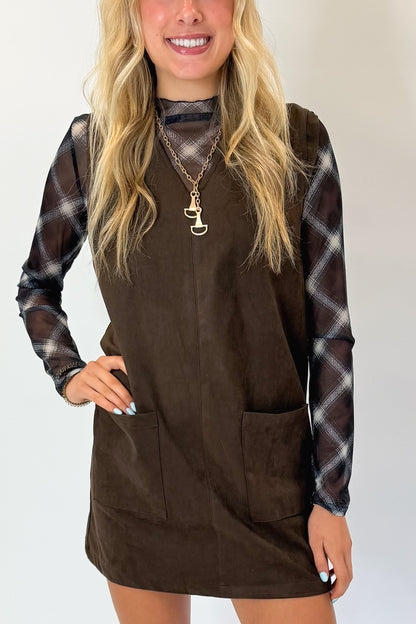 Front detail view of woman wearing Swagger Boutique’s Brown Suede V-Neck Mini Dress with Navy Plaid Mesh Top against white studio background.