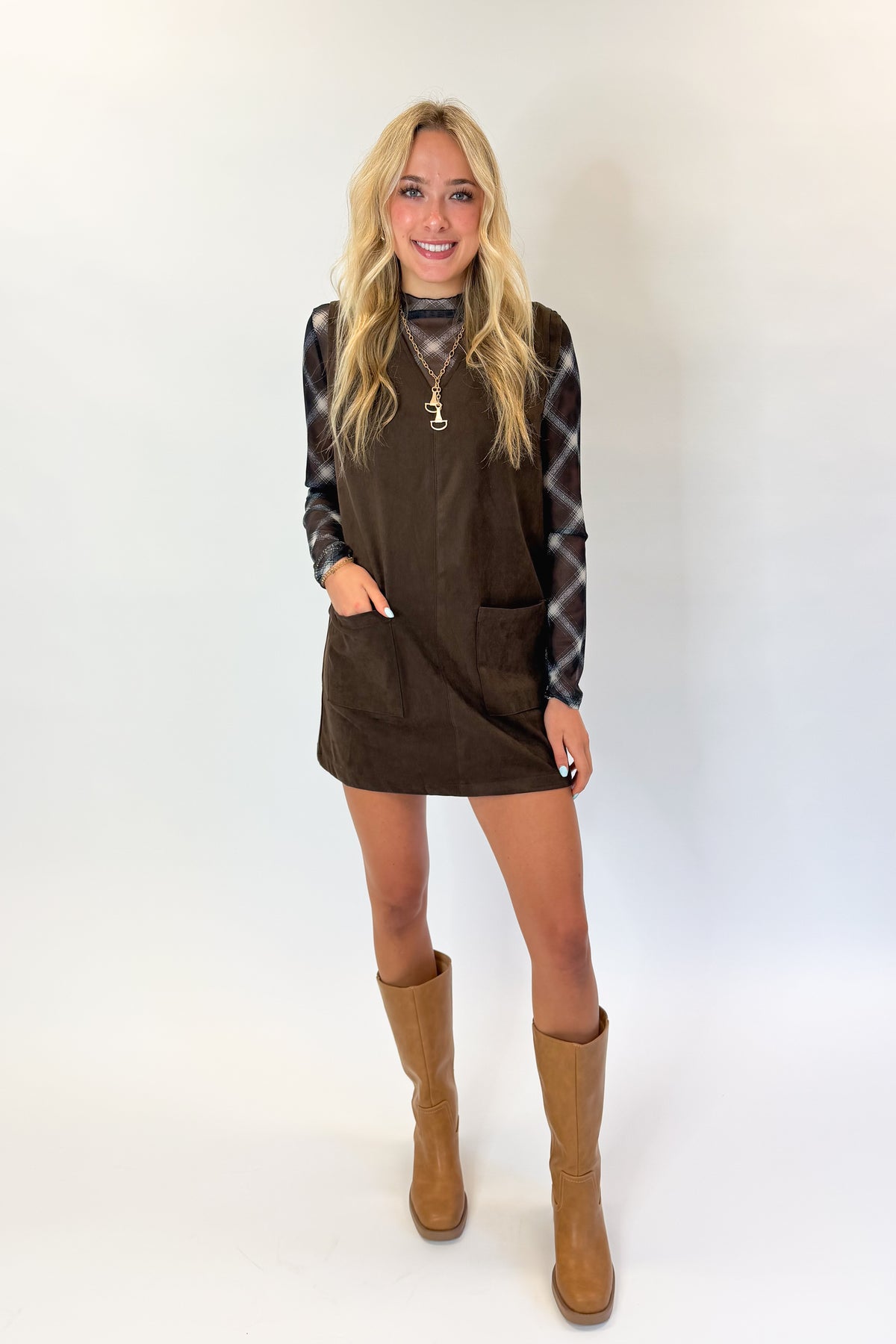 Front view of woman wearing Swagger Boutique’s Brown Suede V-Neck Mini Dress with Navy Plaid Mesh Top against white studio background.