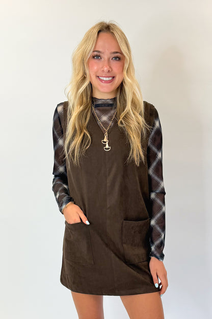 Front view of woman wearing Swagger Boutique’s Brown Suede V-Neck Mini Dress with Navy Plaid Mesh Top against white studio background.