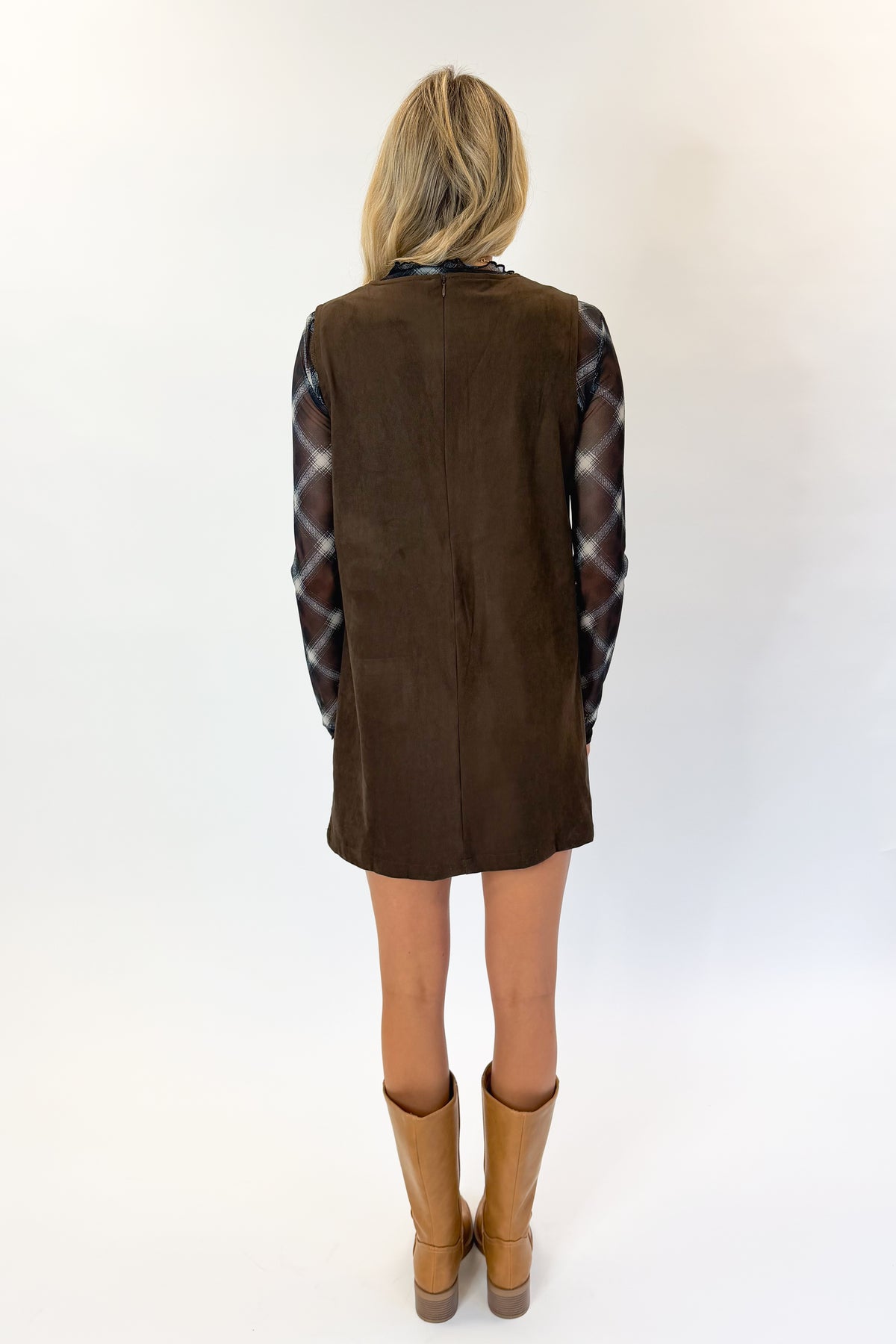 Back view of woman wearing Swagger Boutique’s Brown Suede V-Neck Mini Dress with Navy Plaid Mesh Top against white studio background.