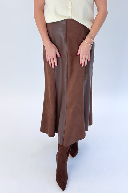 Front view of woman wearing Swagger Boutique’s Cream Sleeveless Button Up Sweater with Brown Suede &amp; Leather Midi Skirt by THML against white studio background.