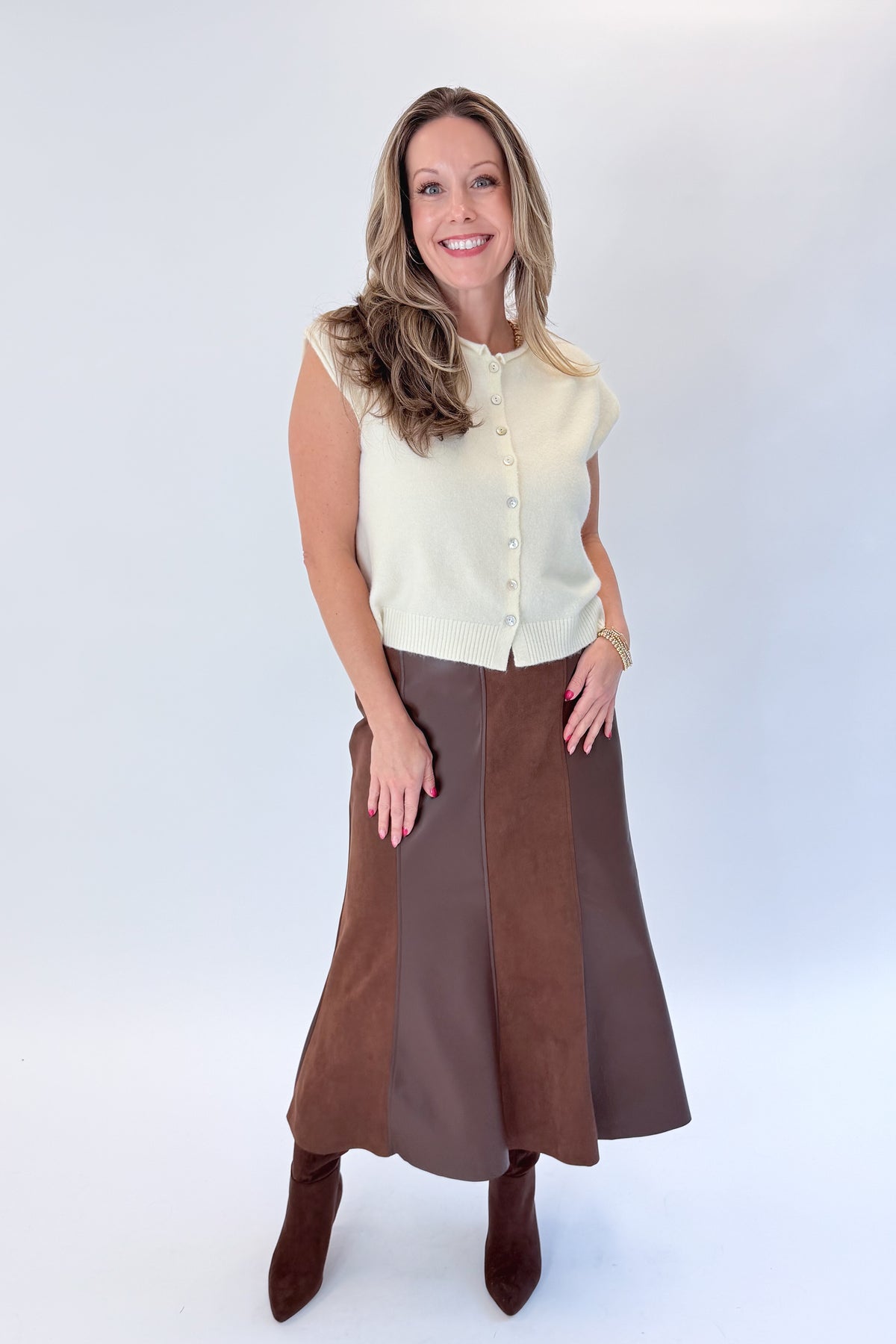 Front view of woman wearing Swagger Boutique’s Cream Sleeveless Button Up Sweater with Brown Suede &amp; Leather Midi Skirt by THML against white studio background.