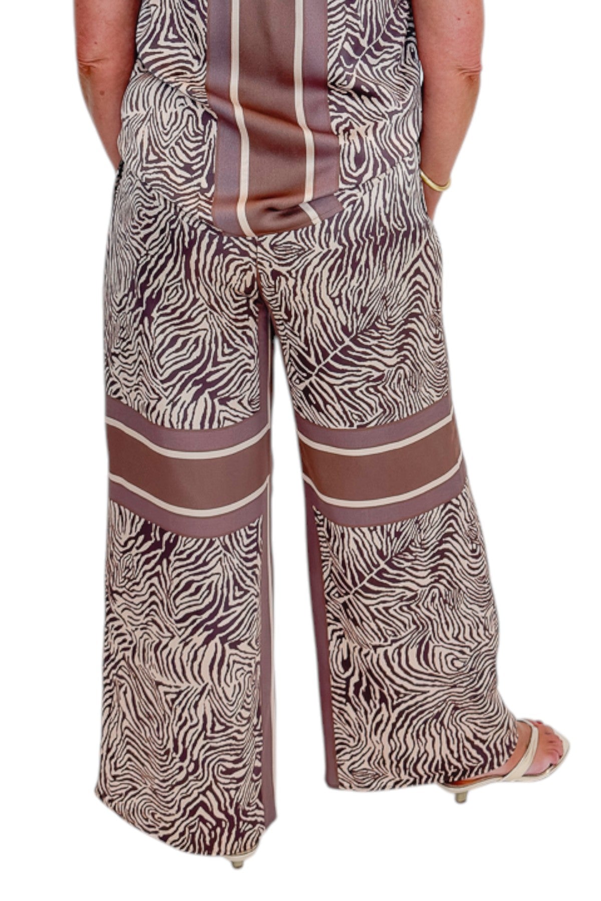 Back view of woman wearing Swagger Boutique’s Brown Zebra Tank by Entro with Wide Leg Pants against white studio background.