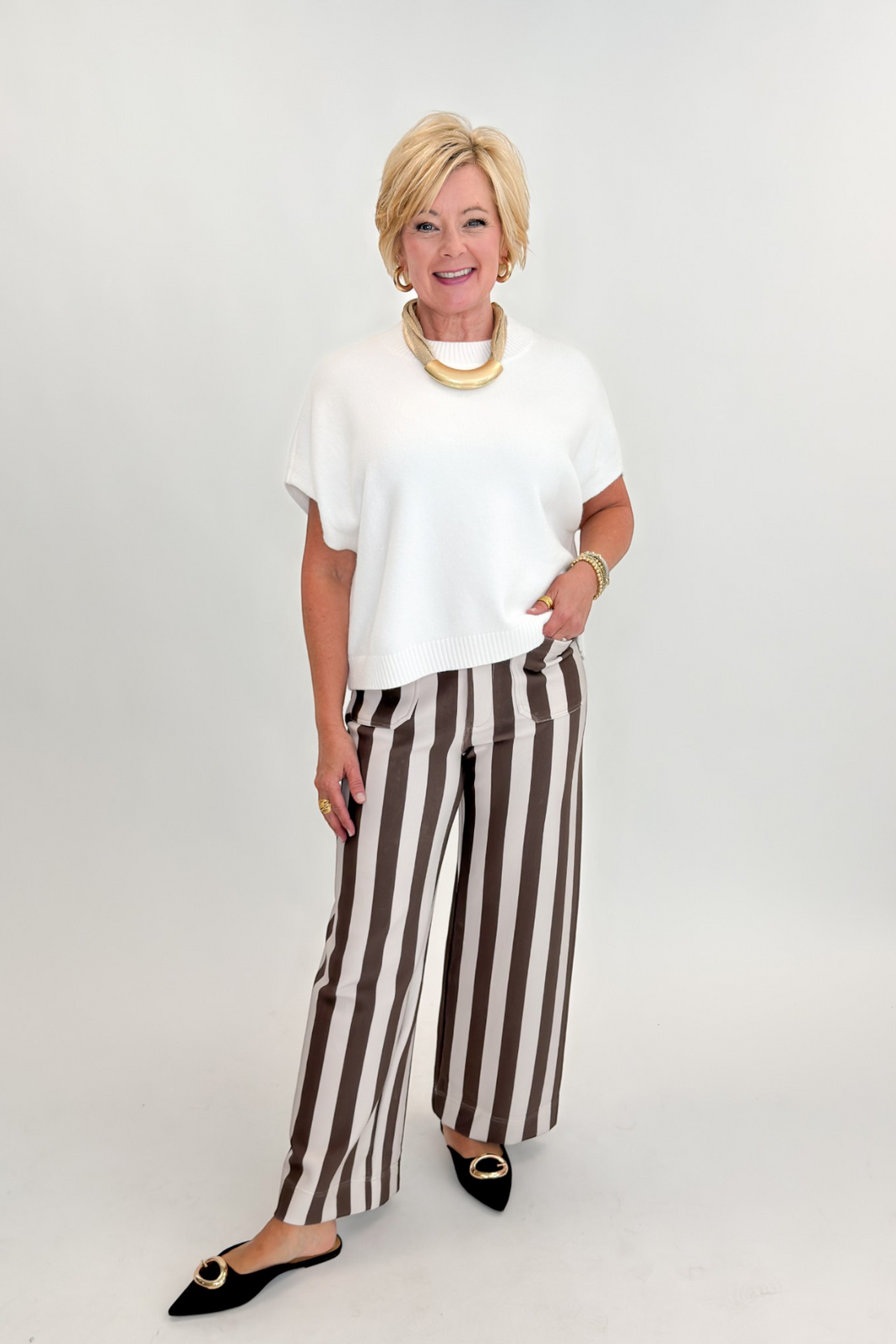 Front view of woman wearing Swagger Boutique’s sweater with Brown &amp; Beige Striped Pants by Entro against white studio background.