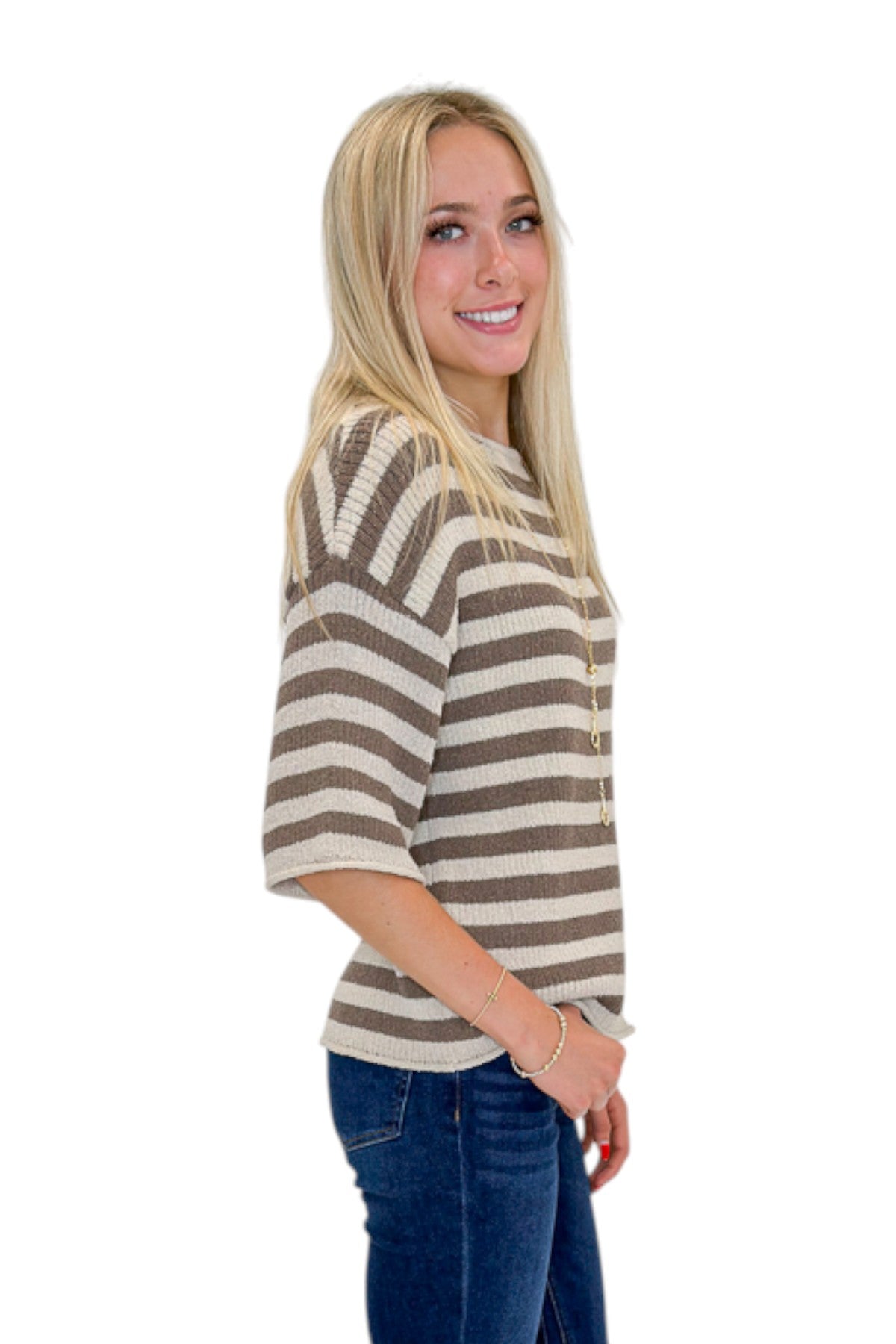 Side view of woman wearing Swagger Boutique’s Brown &amp; Beige Striped Short Sleeve Sweater with jeans against white studio background.