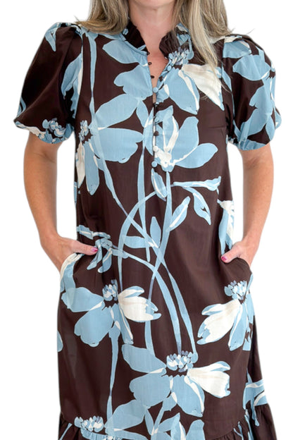 Front detail view of woman wearing Swagger Boutique’s Brown &amp; Blue Floral Midi Dress by Entro against white studio background.