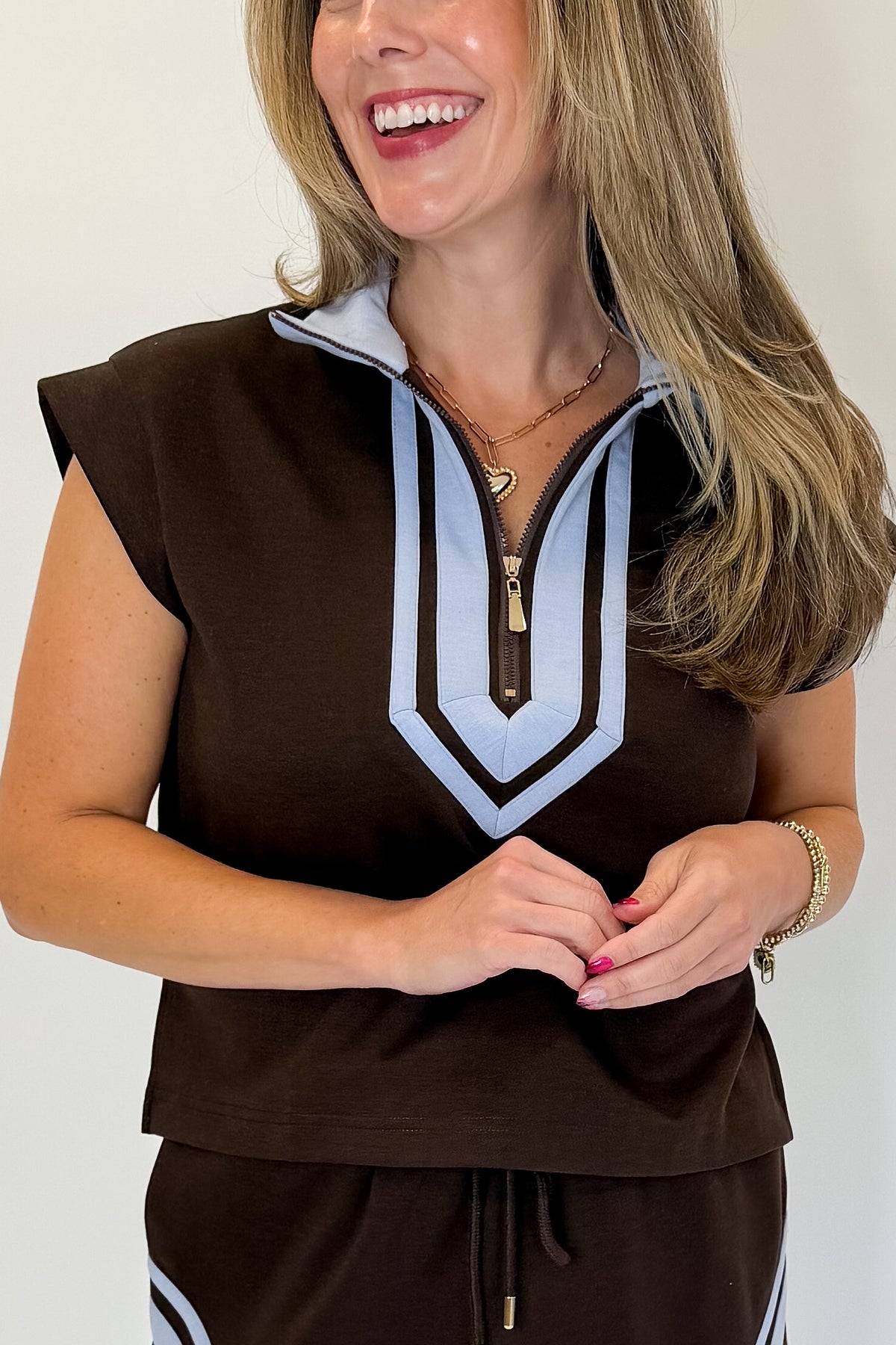 Front detail view of woman wearing Swagger Boutique’s Brown &amp; Blue Mini Skirt and Half Zip Top by Entro against white studio background.
