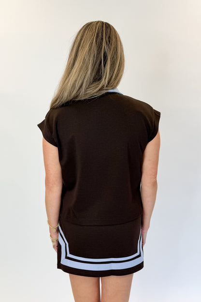 Back view of woman wearing Swagger Boutique’s Brown &amp; Blue Mini Skirt and Half Zip Top by Entro against white studio background.