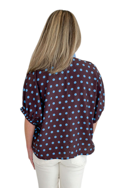 Back view of woman wearing Swagger Boutique’s Brown &amp; Blue Polka Dot Dolman Sleeve Top by Entro with jeans against white studio background.