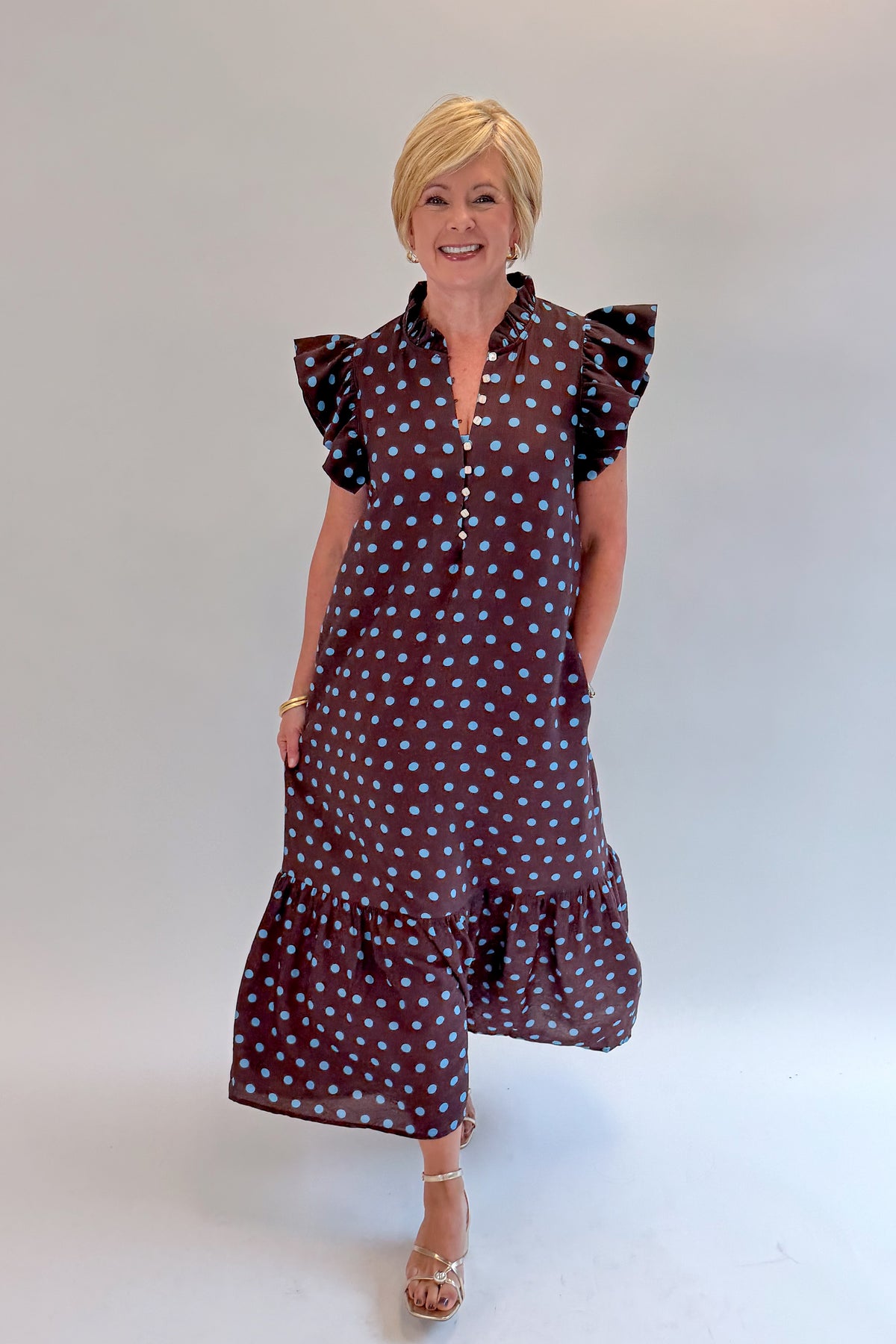 Front view of woman wearing Swagger Boutique’s Brown &amp; Blue Polka Dot Midi Dress by Entro with heels against white studio background. 