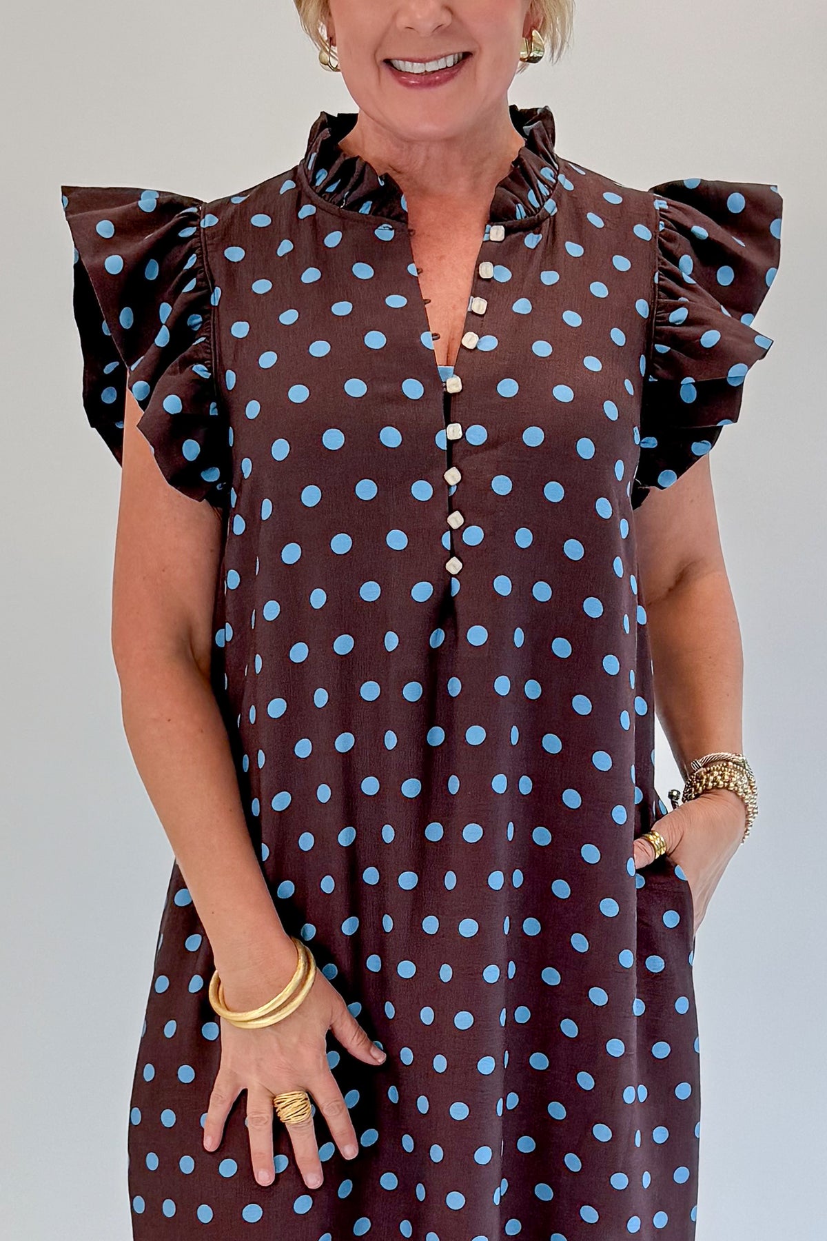 Front detail view of woman wearing Swagger Boutique’s Brown &amp; Blue Polka Dot Midi Dress by Entro with heels against white studio background. 