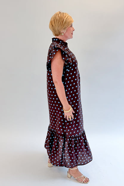 Side view of woman wearing Swagger Boutique’s Brown &amp; Blue Polka Dot Midi Dress by Entro with heels against white studio background. 