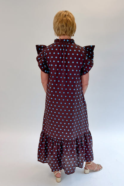 Back view of woman wearing Swagger Boutique’s Brown &amp; Blue Polka Dot Midi Dress by Entro with heels against white studio background. 