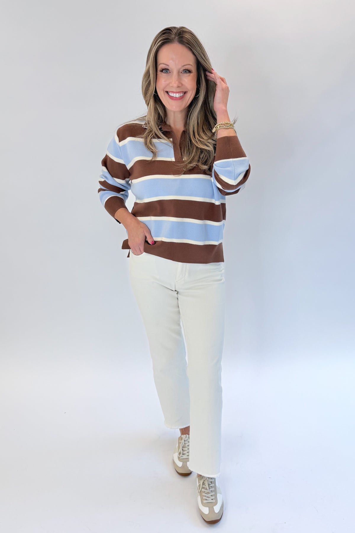 Front view of woman wearing Swagger Boutique’s Brown &amp; Blue Striped Sweater with jeans against white studio background.