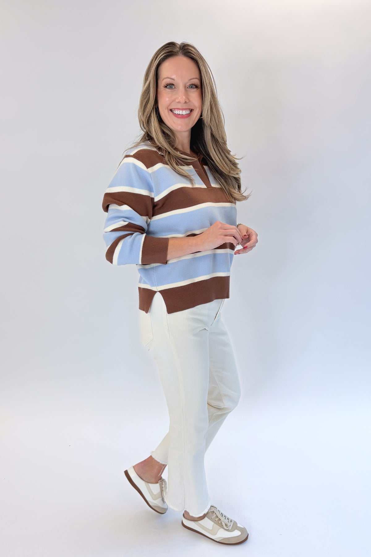 Side view of woman wearing Swagger Boutique’s Brown &amp; Blue Striped Sweater with jeans against white studio background.