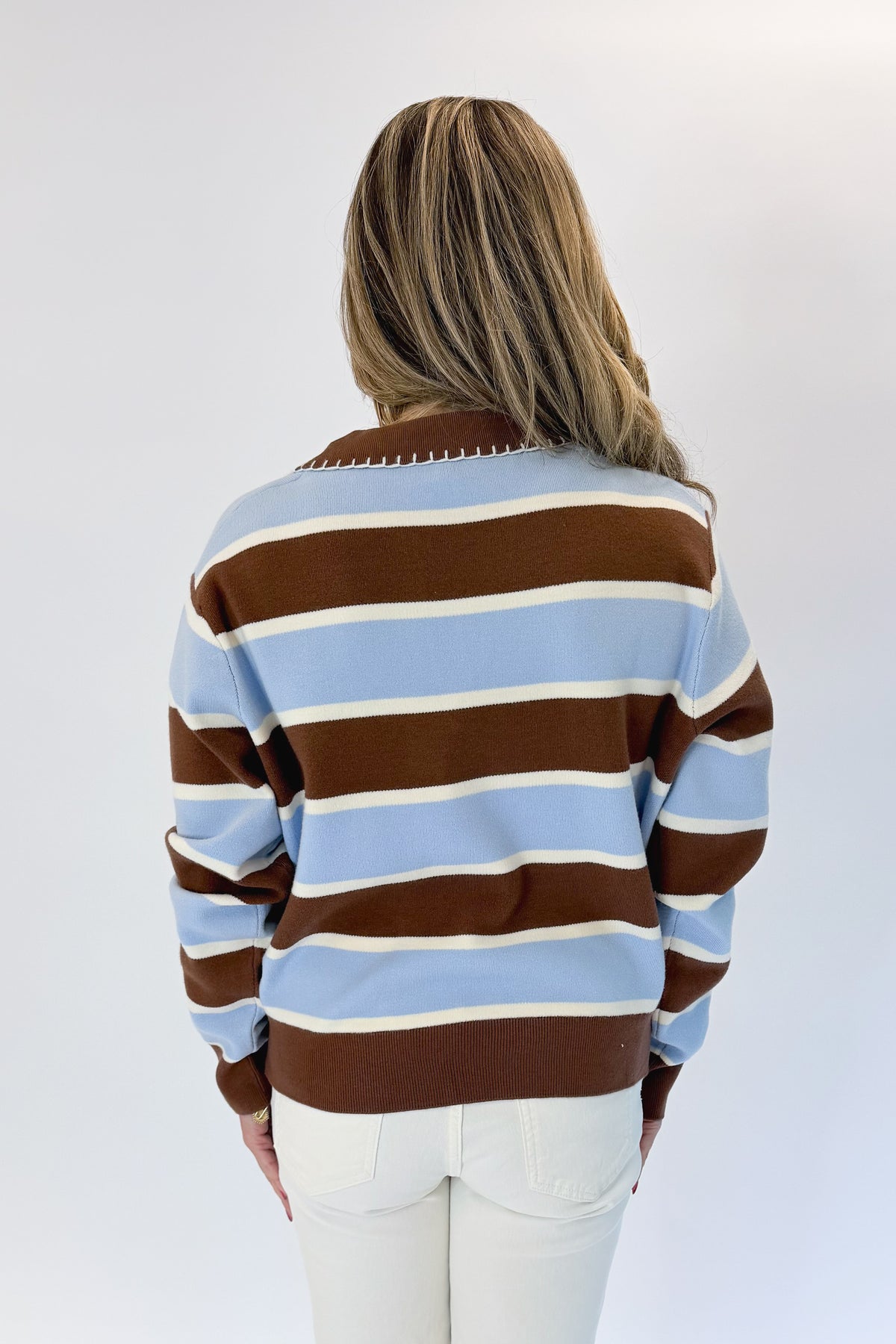 Back view of woman wearing Swagger Boutique’s Brown &amp; Blue Striped Sweater with jeans against white studio background.