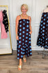 Front view of woman wearing Swagger Boutique’s Works Every Time Brown & Blue Polka Dot Midi Dress by Entro with clothing hanging in the background.