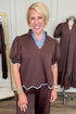 Front view of woman wearing Swagger Boutique’s Brown & Blue Scalloped Top by Entro with matching pants with clothing hanging in the background.