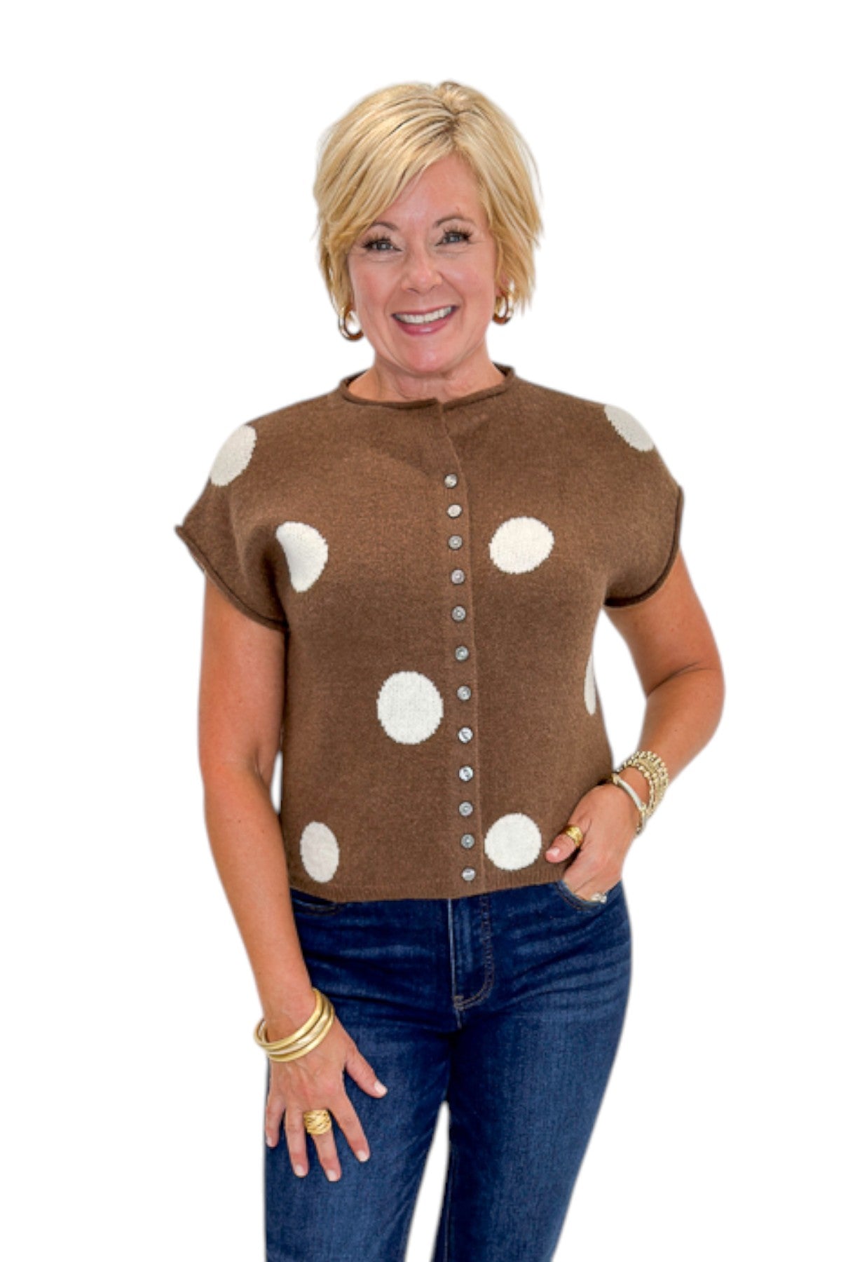 Front view of woman wearing Swagger Boutique’s Brown &amp; Cream Polka Dot Sleeveless Button Up Sweater by Entro with jeans against white studio background.
