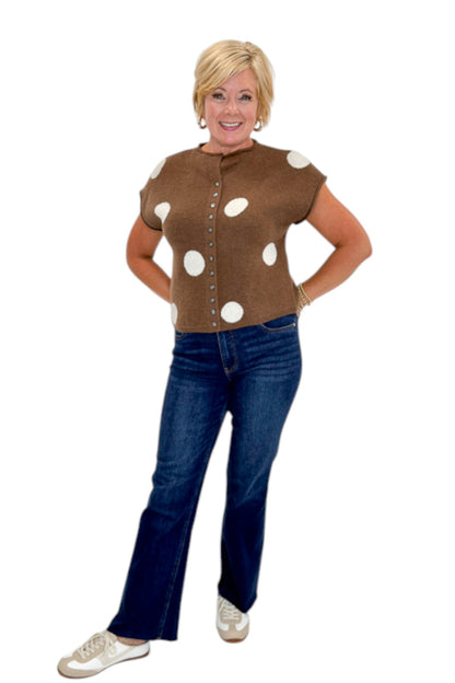 Front view of woman wearing Swagger Boutique’s Brown &amp; Cream Polka Dot Sleeveless Button Up Sweater by Entro with jeans against white studio background.