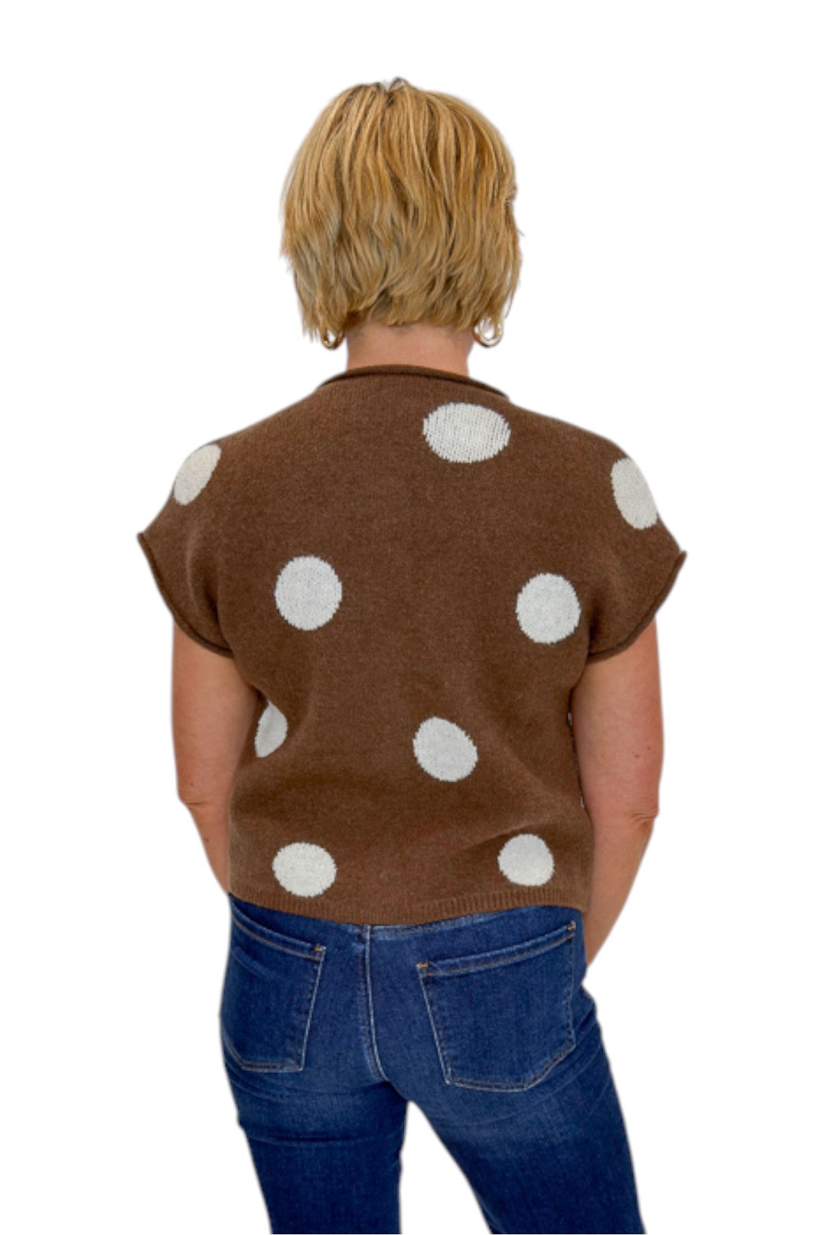 Back view of woman wearing Swagger Boutique’s Brown &amp; Cream Polka Dot Sleeveless Button Up Sweater by Entro with jeans against white studio background.