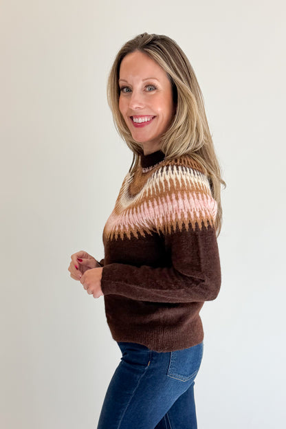 Side view of woman wearing Swagger Boutique’s Brown &amp; Pink Fair Isle Sweater with jeans against white studio background.