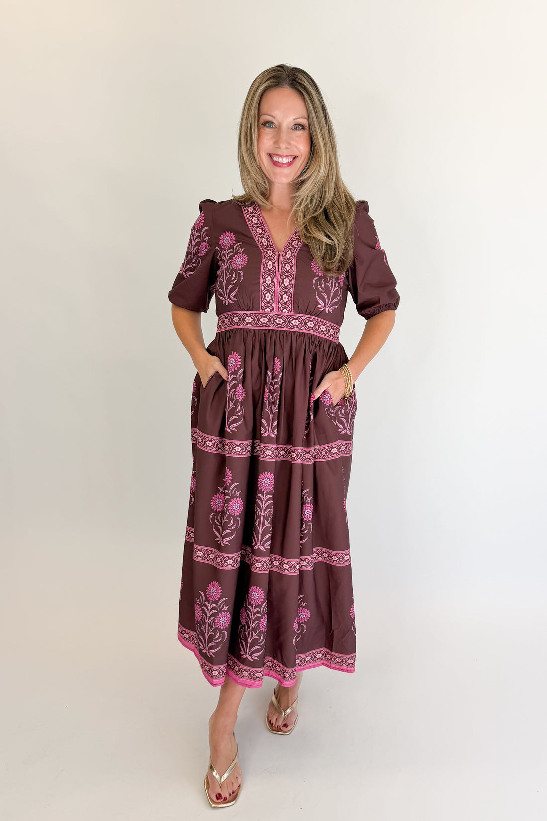 Front view of woman wearing Swagger Boutique’s Brown &amp; Pink Printed Midi Dress with heels against white studio background.