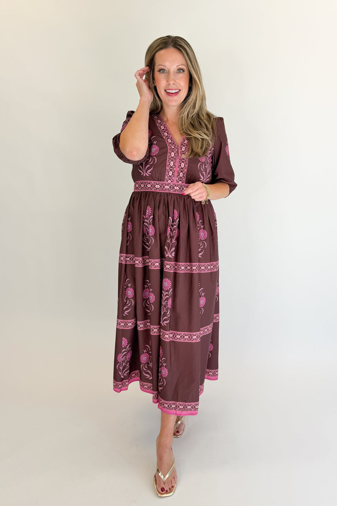 Front view of woman wearing Swagger Boutique’s Brown &amp; Pink Printed Midi Dress with heels against white studio background.