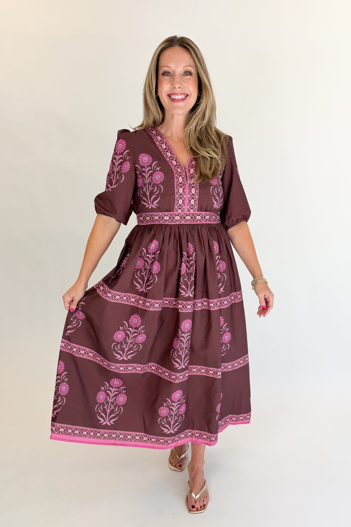 Front view of woman wearing Swagger Boutique’s Brown &amp; Pink Printed Midi Dress with heels against white studio background.