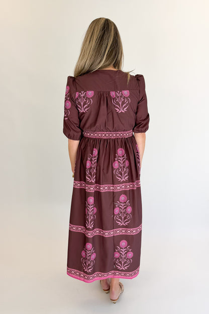 Back view of woman wearing Swagger Boutique’s Brown &amp; Pink Printed Midi Dress with heels against white studio background.