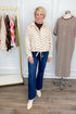 Front view of woman wearing Swagger Boutique’s Brown Polka Dot Denim Jacket with jeans with clothing hanging in the background.