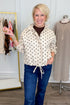 Front view of woman wearing Swagger Boutique’s Brown Polka Dot Denim Jacket with jeans with clothing hanging in the background.