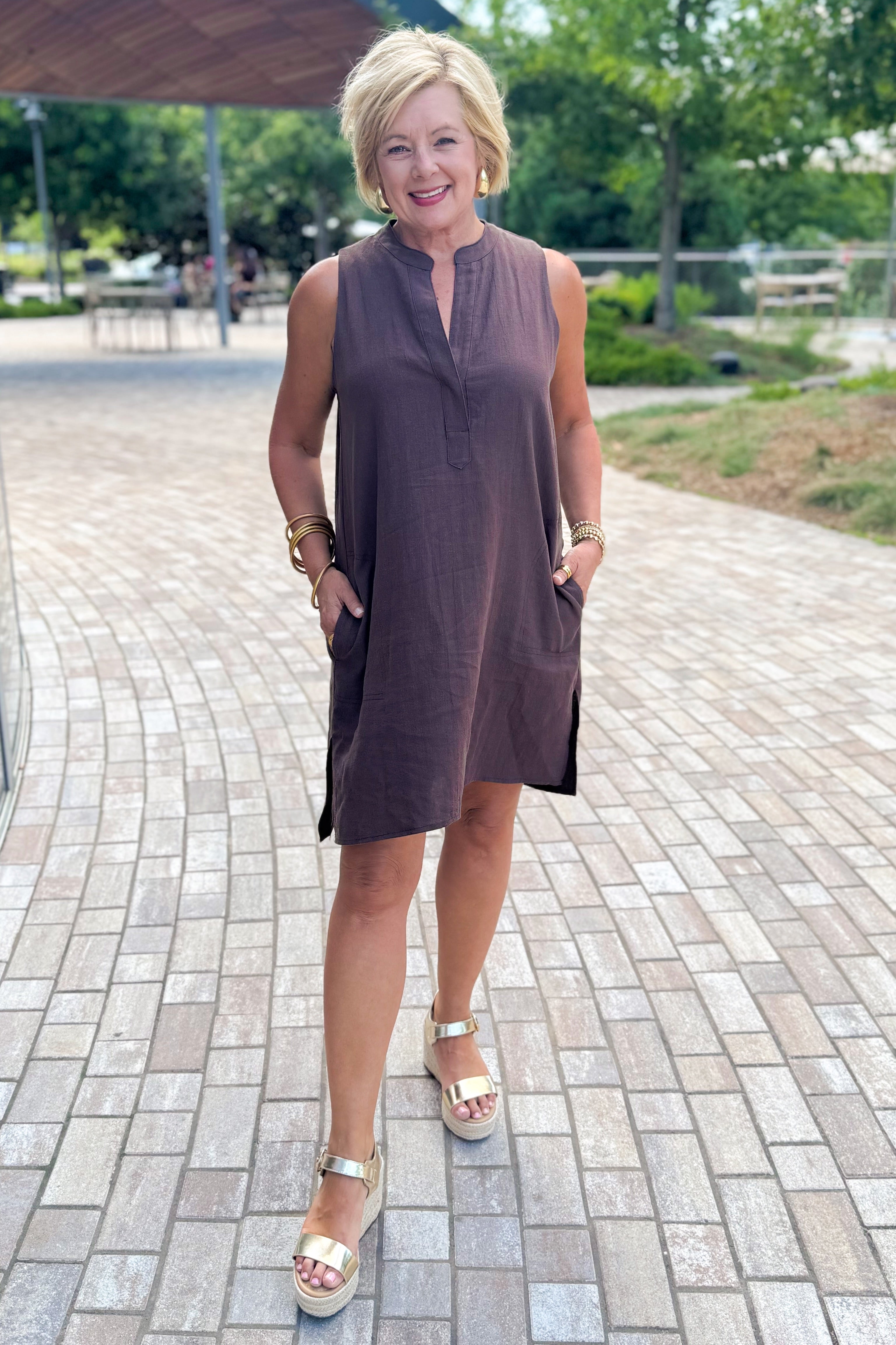 Woman wearing a brown dress standing outside at a park.
