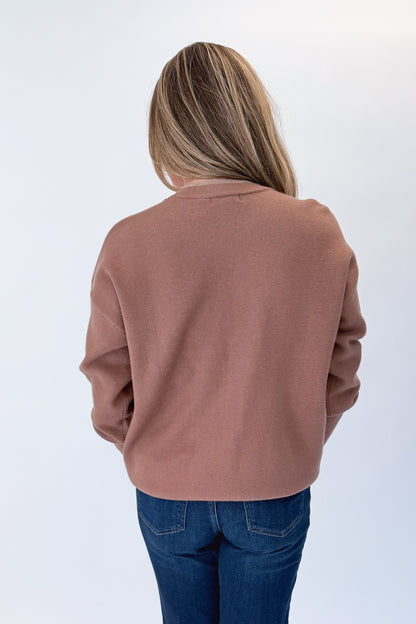 Back view of woman wearing Swagger Boutique’s Brown &amp; Taupe Double Band Sweater with jeans against white studio background.