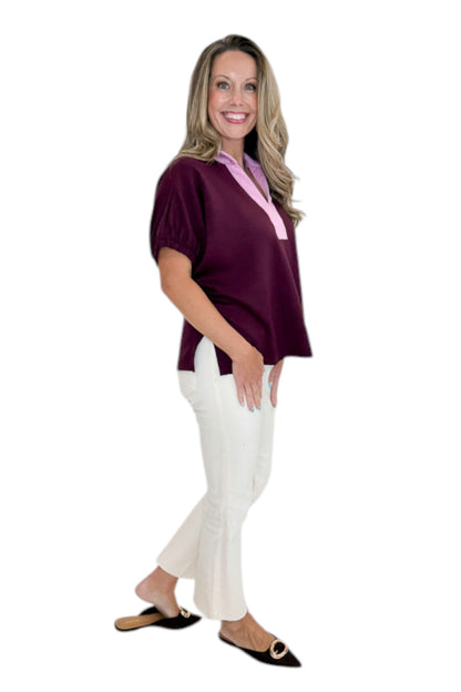 Side view of woman wearing Swagger Boutique’s Burgundy &amp; Pink Contrast Dolman Sleeve Top by Entro with jeans against white studio background.
