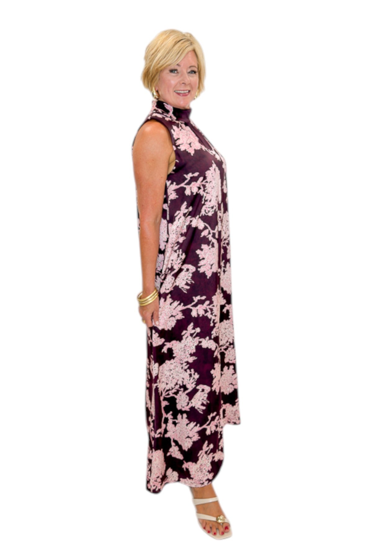 Side view of woman wearing Swagger Boutique’s Burgundy &amp; Pink Printed Maxi Dress by Entro with sandals against white studio background.