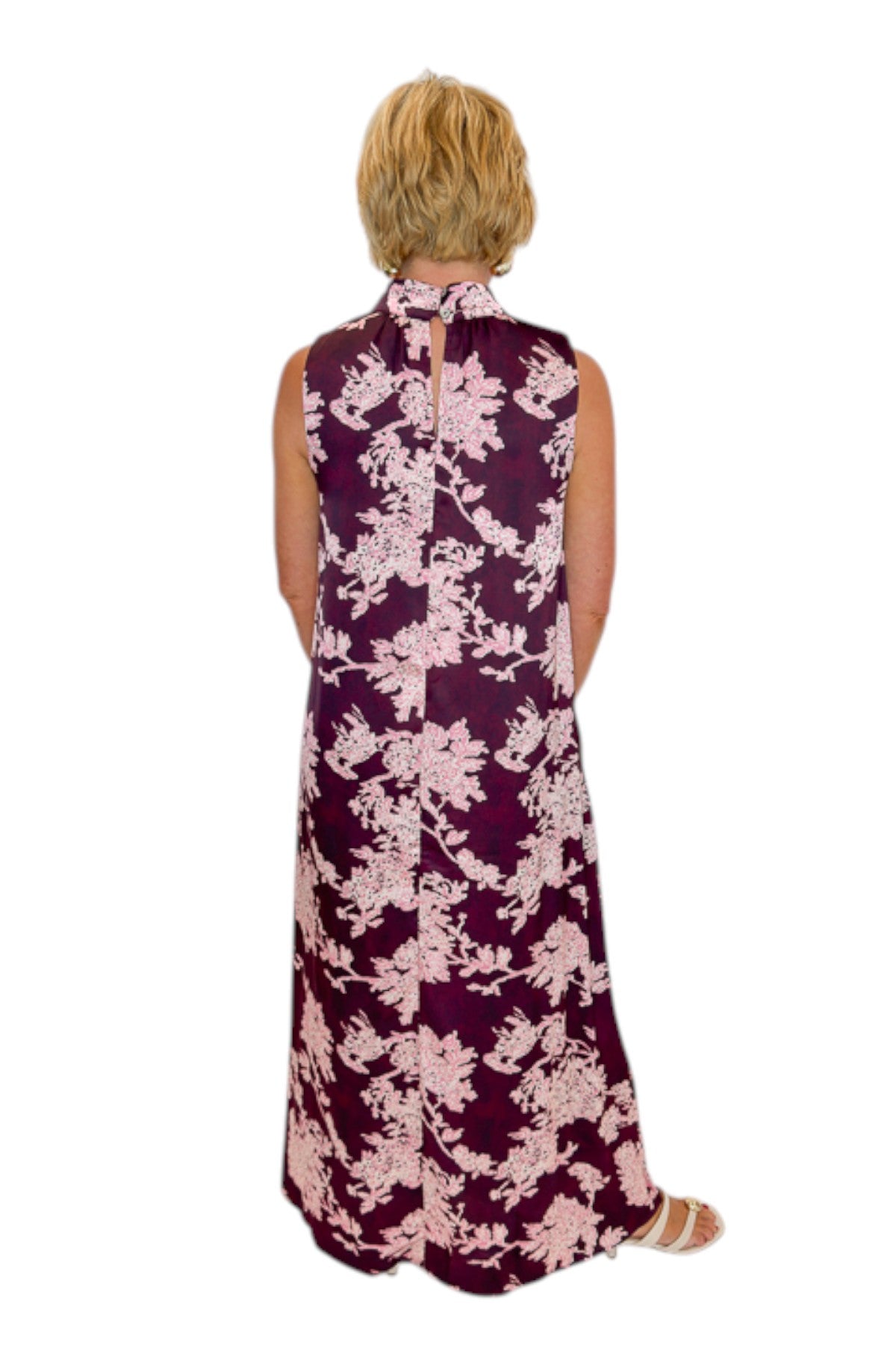 Back view of woman wearing Swagger Boutique’s Burgundy &amp; Pink Printed Maxi Dress by Entro with sandals against white studio background.