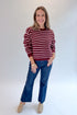 Front view of woman wearing Swagger Boutique’s Burgundy & Pink Striped Sweater with jeans against white studio background.